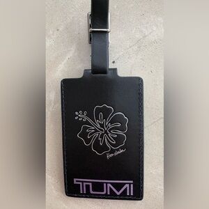 Black leather TUMI luggage tag, embossed with Honolulu and a hibiscus flower.